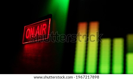 ON AIR sign with red and green lights behind of digital audio metering visual screen. Recording studio.