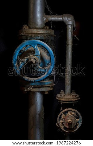 still life light painting photography, industrial water pipes and valve with a black background with rusty metal and spider webs on pipes and valve