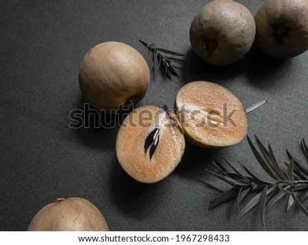 Slice of Sapodilla with green leaves on black background