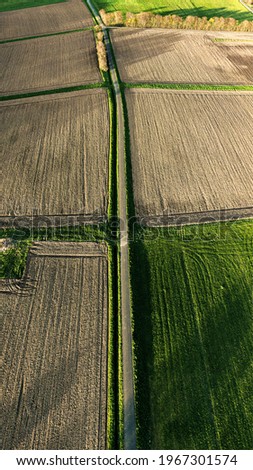 An aerial shot of a beautifully cultivated green farmland during sunset