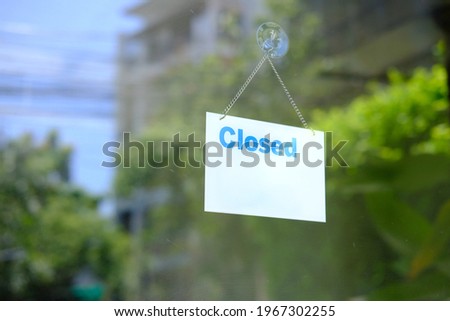 Hangs a card with information about the store closing on a shop window