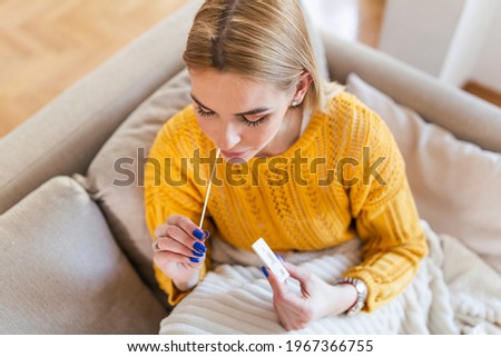 woman using cotton swab while doing coronavirus PCR test at home. Woman using coronavirus rapid diagnostic test. Young woman at home using a nasal swab for COVID-19. Royalty-Free Stock Photo #1967366755