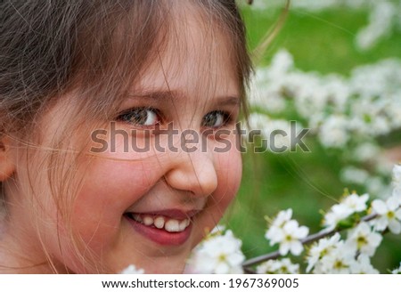Portrait of Young smiling Girl Teen.  Beautiful smiling girl near blossom cherry tree with white flowers in spring garden. Springtime concept.                               