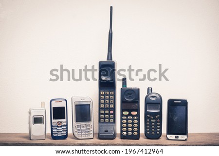 Group of old and obsolete mobile phone or cell phone on old wood with a light rough background Royalty-Free Stock Photo #1967412964