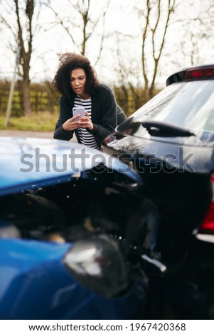 Female driver taking photos of road traffic accident on mobile phone for insurance claim