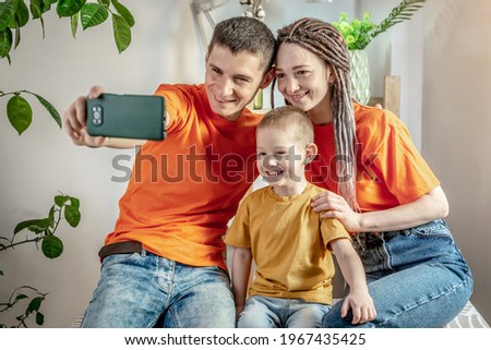 Cheerful and funny dad, mom and child are taking pictures on a mobile phone camera at home. Concept of a harmonious happy family, caring and spending time together.