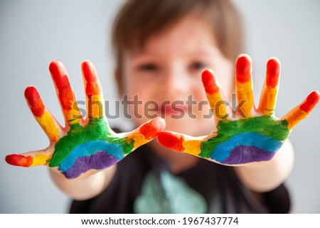 Cute little girl showing her hands with rainbow painted on them