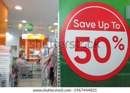 Sale up to 50% off text on a signboard inside a popular fashion and cosmetic store.