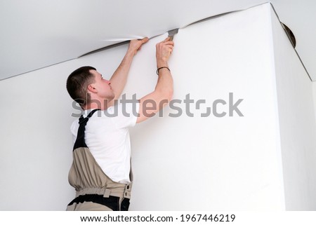 worker installs a stretch ceiling. Construction and renovation concept Royalty-Free Stock Photo #1967446219