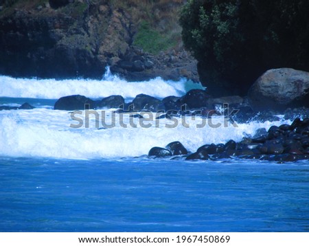 Waves crashing on the rocks, a beach scene enhanced with a blue filter.