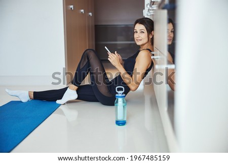 Attractive sporty woman using smartphone at home