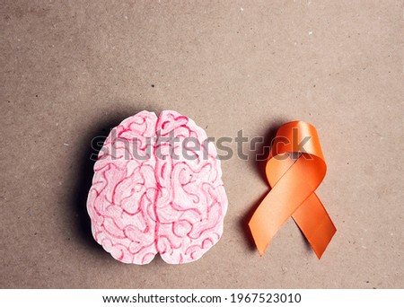World Multiple Sclerosis Day. Orange awareness ribbon and brain symbol on a brown background. Royalty-Free Stock Photo #1967523010