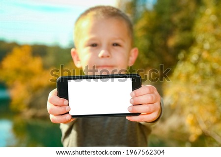 Happy child with phone taking selfie in nature in the park travel