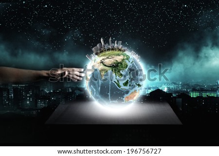 Close up of human hand touching Earth planet with finger. Elements of this image are furnished by NASA