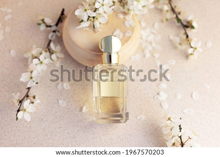 glass perfume bottle with fragments of wood and sakura flowers on a light background. Concept of delicate feminine floral perfume Royalty-Free Stock Photo #1967570203