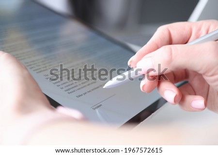 Woman hand holds stylus and puts an electronic signature in contract on tablet Royalty-Free Stock Photo #1967572615