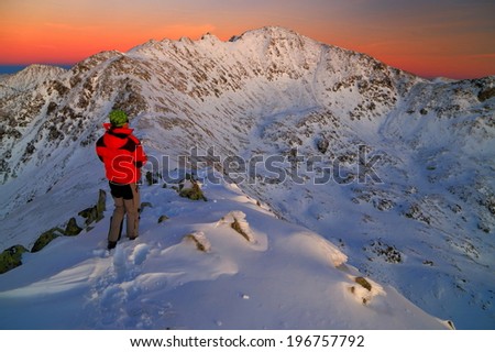 Photographer taking pictures on snowy mountains at sunset 