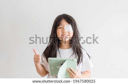 Lazy Eye amblyopia in children.Eye care.Little asian girl covered up with a special patch online learning at home.Occlusion therapy using an eye patch.Children care.child online learning education. Royalty-Free Stock Photo #1967580025
