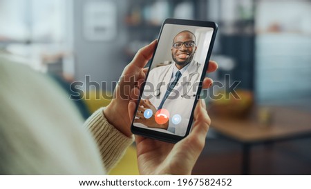 Close Up of a Female Has a Video Call with Her Female Family Doctor on Smartphone from Living Room. Ill-Feeling Woman Making a Call from Home with Physician Over the Internet. Royalty-Free Stock Photo #1967582452