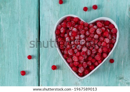 frozen red currants on wooden surface