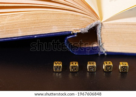 The book is open on the table and the word is made up of dice, black background.