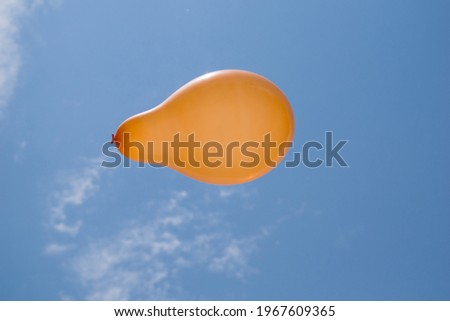 picture of orange balloon flying under blue sky with white clouds.