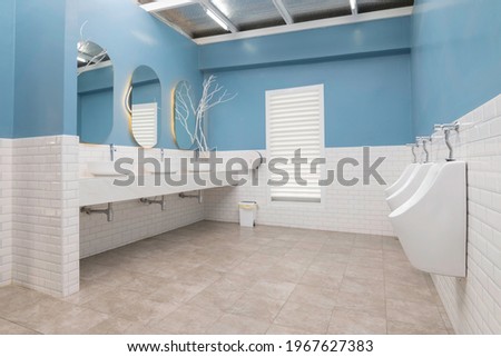 Row of modern white ceramic washbasins in a public blue-and-white bathroom or restaurant or hotel or shopping mall interior design. Royalty-Free Stock Photo #1967627383