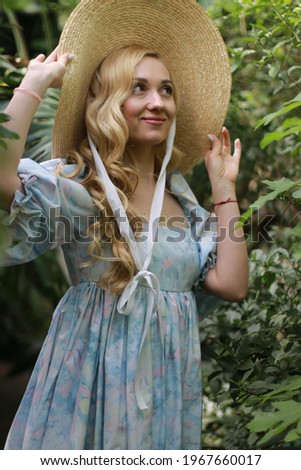 Girl in a short blue dress and hat in the greenhouse. Fabulous photo session in orangerie