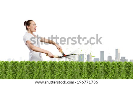 Young attractive businesswoman cutting green lawn. Greenery concept