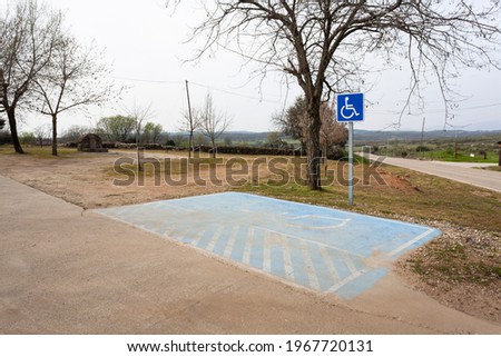 Parking space reserved for the disabled in a public picnic area with a stone fountain in the background