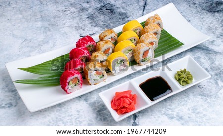 Sushi set. California rolls, dragon rolls, cheese rolls on plate isolate on marble. Wasabi, soy sauce and gari in plate isolated on marble.