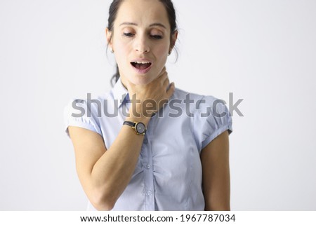 Frustrated woman holds her throat with her hand and coughs Royalty-Free Stock Photo #1967787034