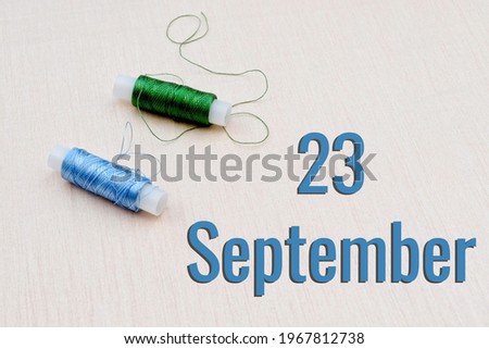 Handicraft calendar 23 september. Skeins of green and blue threads for embroidery on beige background. Handmade concept.