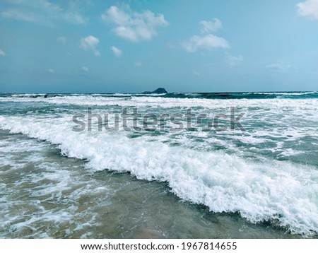 Beautiful foamy waves with a little island on the horizon