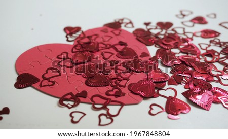 Many shiny sparkling hearts on big red puzzle shaped jigsaw on white table background. Celebrate Valentines day