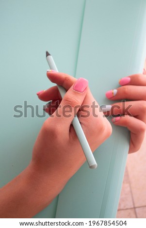 Closeup image woman hand with pencil on teal background