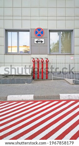Fire hydrants on wall of building for connecting with fire truck. Road marking and sign for fire tracks parking