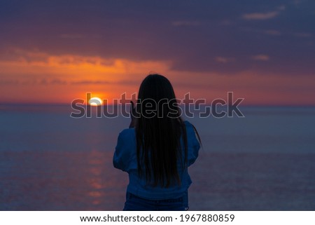 girl shoots the sunset on the sea