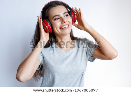 Young smiling woman in modern headphones listening music. White background. Woman expresses joyful emotions.