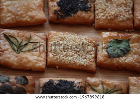  Homemade crackers decorated with herb leaves, sesame seeds, poppy seeds and salt