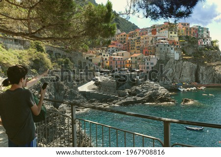 Manarola, Liguria, Italy. June 2020. Amazing view of the seaside village. The colorful houses leaning against the rock near the sea are fascinating. A guy takes a picture with his smartphone.
