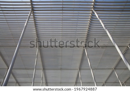 Framework of steel grid roof above passageway. Abstract modern architecture and mimalist interior with pillars, girders and rails or lath. Hi-tech polygonal geometric structure of parallel lines.