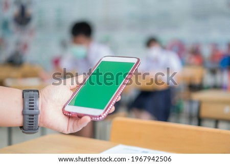 Mock up green screen smart phone, Application digital smartphone on exam testroom while Students school wear face mask learning project searching app in online classroom learners in modern technology