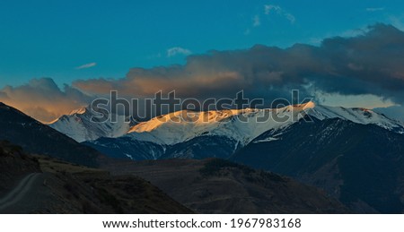 Russia. North-Eastern Caucasus, Republic of Dagestan. Shrouded in clouds and illuminated by the morning sun, the snow-capped peaks of the mountains near the city of Agwali. Royalty-Free Stock Photo #1967983168