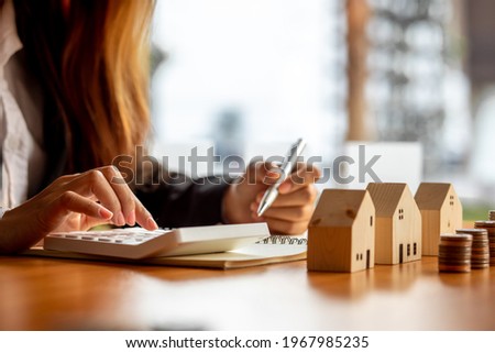 Close up wooden toy house with business woman signs a purchase contract or mortgage for a home, Real estate concept.	