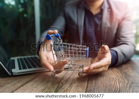 Online shopping. Gold credit card and smartphone in small shopping cart with icon customer network connection. Conceptual of internet shopping and e-commerce on wooden table background