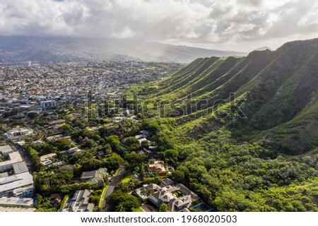 Aerial view of Honolulu suburbs located at the food of steep green volcanic mountain in Hawaii