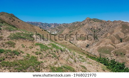A panoramic view on Daqing mountains in Inner Mongolia. Endless mountain chains. The slopes are mostly barren, overgrown with small bushes and grass. Desolated landscape. Bio diversity of a region Royalty-Free Stock Photo #1968021970