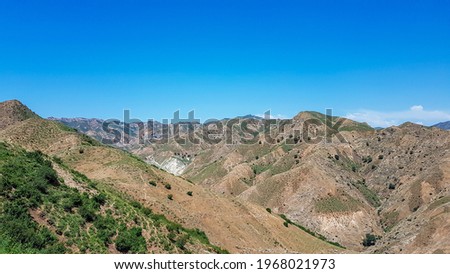 A panoramic view on Daqing mountains in Inner Mongolia. Endless mountain chains. The slopes are mostly barren, overgrown with small bushes and grass. Desolated landscape. Bio diversity of a region Royalty-Free Stock Photo #1968021973