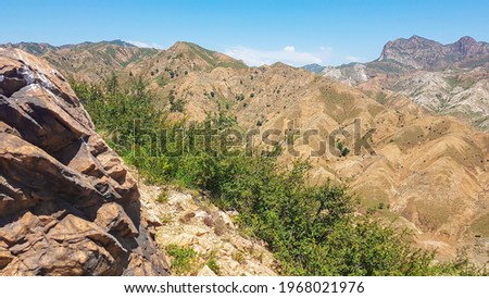 A panoramic view on Daqing mountains in Inner Mongolia. Endless mountain chains. The slopes are mostly barren, overgrown with small bushes and grass. Desolated landscape. Bio diversity of a region Royalty-Free Stock Photo #1968021976